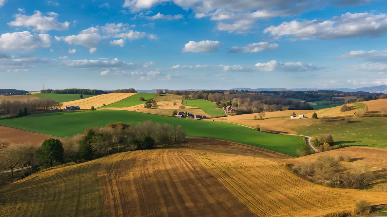 Gliding drone showing rolling fields over rural farmland, highlighting plowed rows and winding road