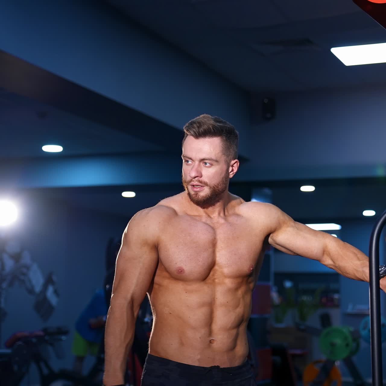 Man with perfect body train muscles on sport equipment. View from the side on handsome man with perfect body