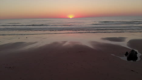 stunning landscape of sunset over the calm ocean with waves washing up on the beach in summer in algarve, portugal. - aerial drone shot
