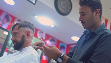 barbero corta el cabello de un hombre con una navaja de borde recto en una barbería
