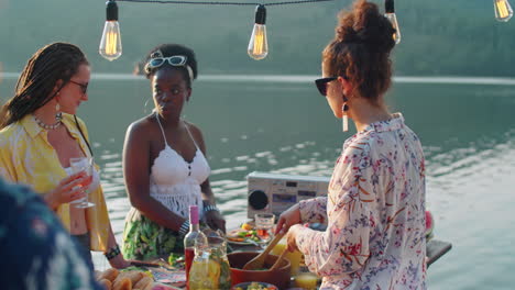 girls cooking food for outdoor party on lake pier