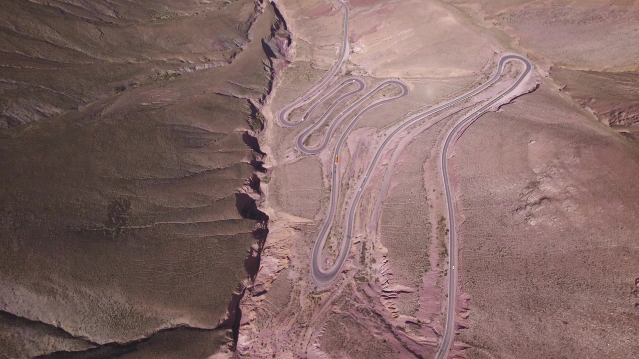 4K drone aerial view of Cuesta de Lipán, Jujuy, Argentina. Spectacular winding mountain road climbing through the Andes with dramatic curves, rugged landscapes and breathtaking high altitude scenery.