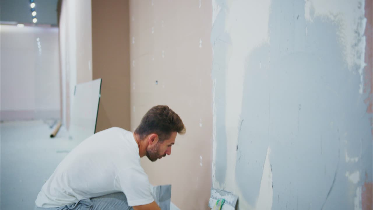 A Skilled Painter in Action: Transforming a Wall with Care and Precision in a Home Renovation Project Using Roller and Paint Tools