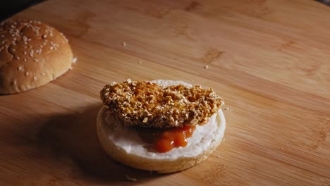 preparing healthy burger with mayonnaise, ketchup, chicken nugget, cheese, tomato, and lettuce