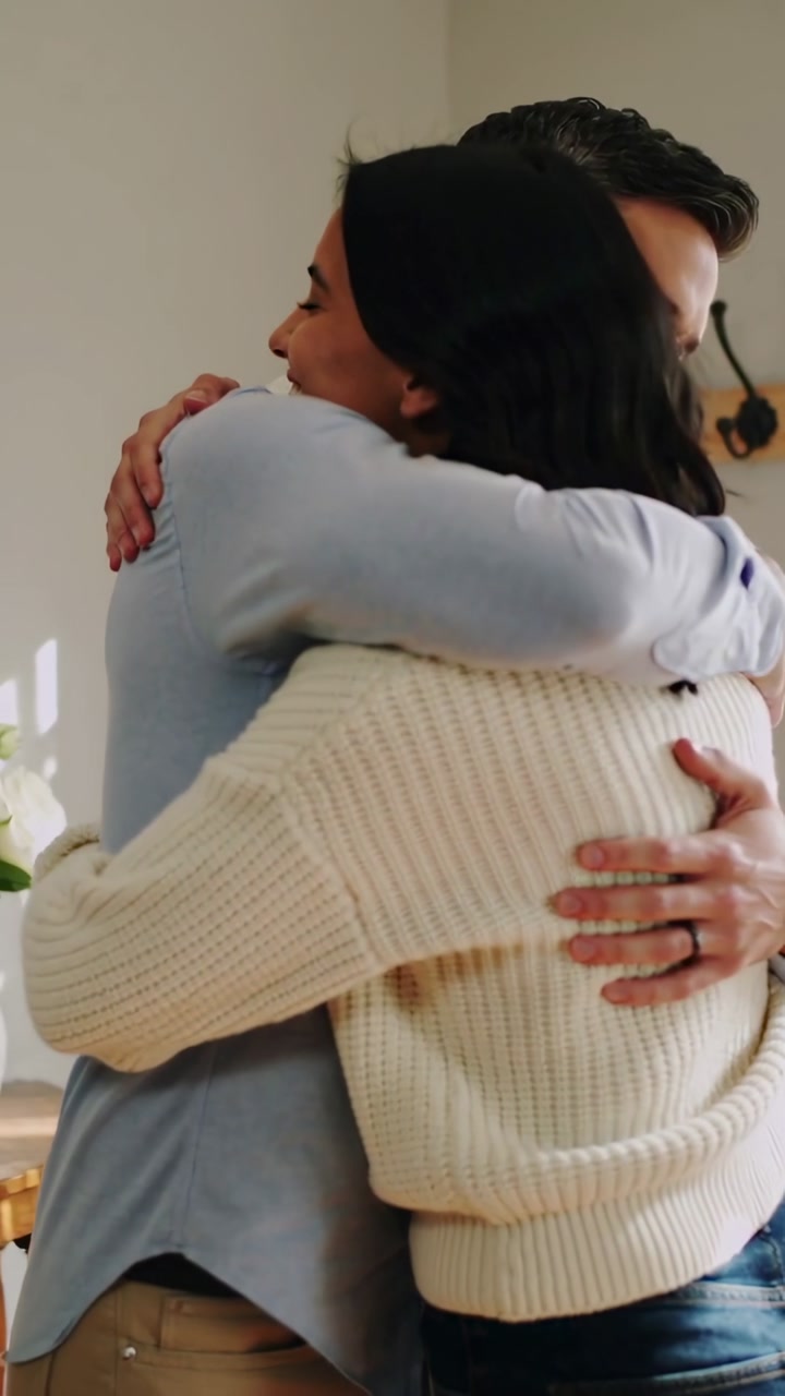 Man and woman smiling, reaching and embracing at entry, showing comfort, ring visible, wellness