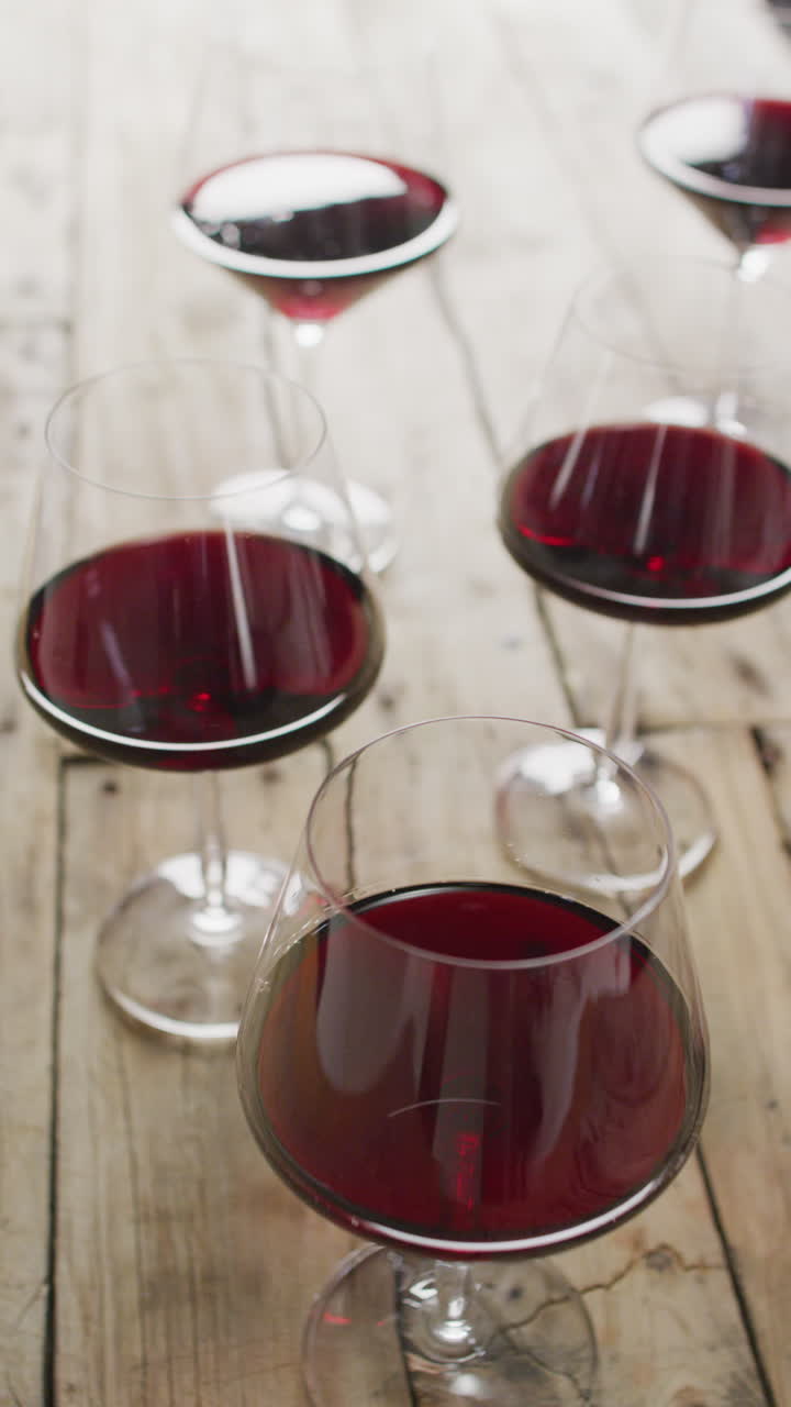 Video verticale di bicchieri di vino rosso su superficie di legno