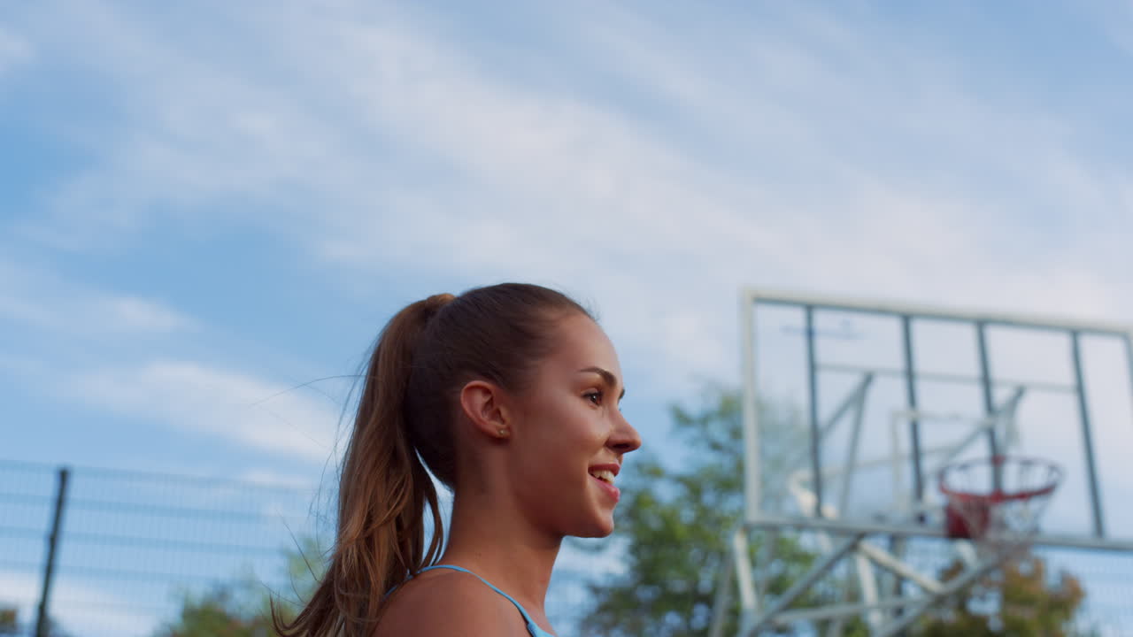 mujer sonriente caminando con un amigo en el patio de baloncesto. mujer deportista jugando
