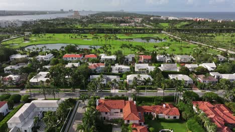 Aerial-view-of-a-Palm-Beach,-Florida-coastal-neighborhood-with-lush-greenery,-white-roofed-houses,-and-The-Breakers-golf-course