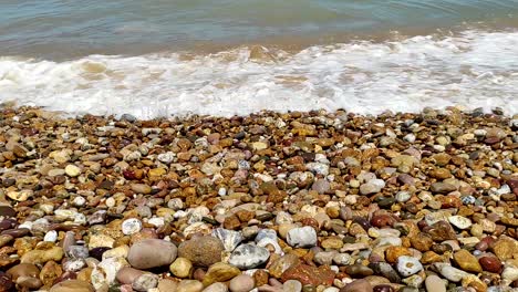 close-up blue waves breaking over a colorful rocky shoreline-1