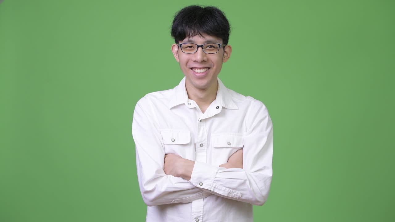 젊은 행복한 아시아 사업가 팔을 고 미소 짓고