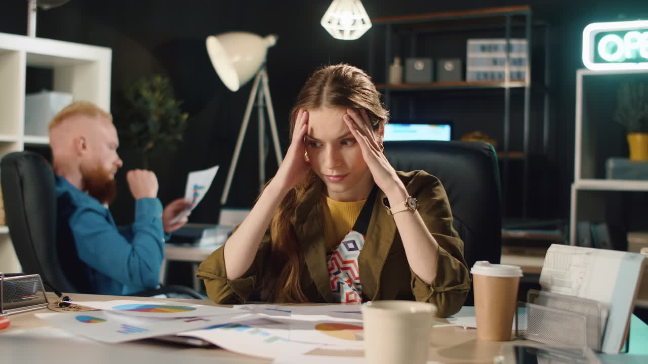 una mujer de negocios molesta comprobando errores en documentos en una oficina oscura.