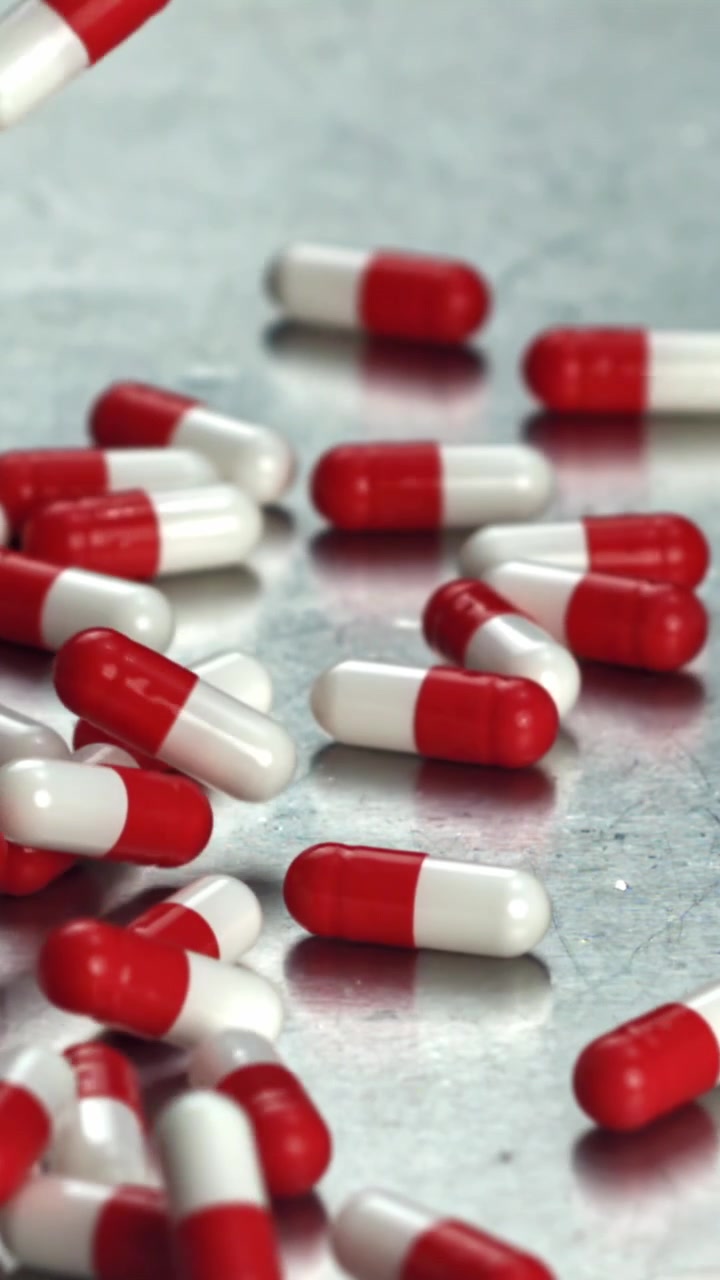 Capsule rosse e bianche che cadono al rallentatore su una superficie metallica