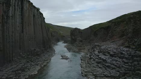 aerial forward along basalt columns cliffs down stream