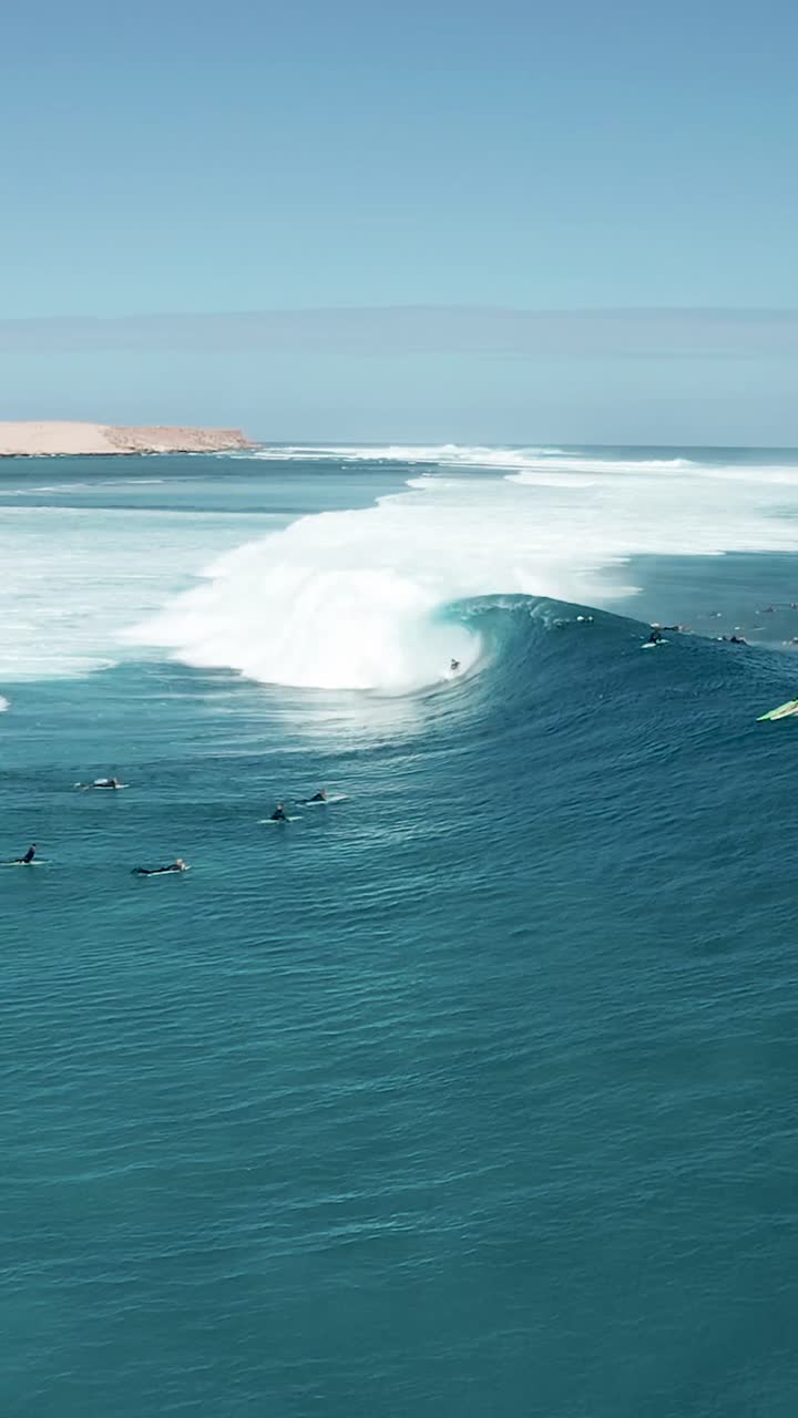 바다의 큰 파도에서 서핑하는 젊은이들의 수직