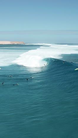 une photo verticale d'un groupe de jeunes surfeurs sur les grandes vagues de l'océan