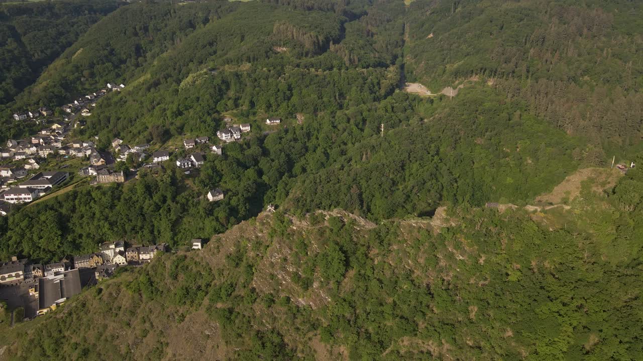 vuelo aéreo sobre una montaña que revela una gran cantidad de casas construidas en el valle de cochem, alemania