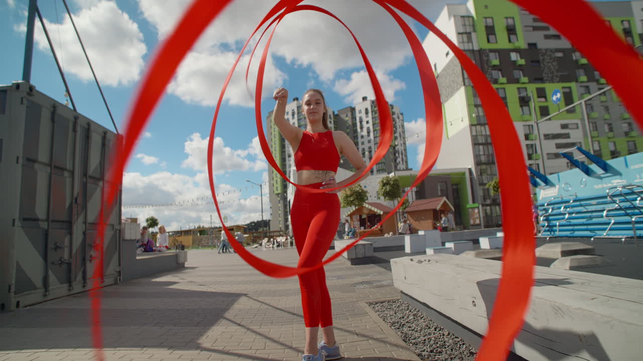 Woman Twirling Red Ribbons in Urban Setting