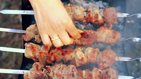 bbq meat cooking on charcoal. closeup. woman tasting piece of meat