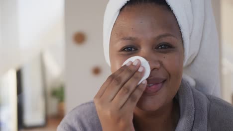 happy african american plus size woman using cotton pad for cleansing face, unaltered, slow motion