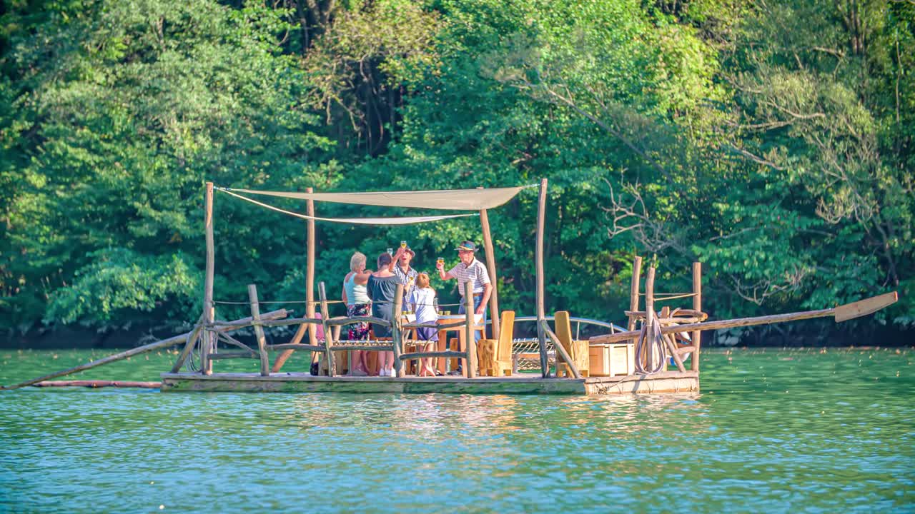 family cheers with a drink. Tranquil river Drava journey on log raft