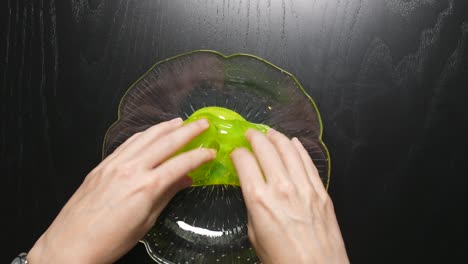 Female-Fingers-kneading-a-yellow-transparent-slime-in-a-glass-bowl