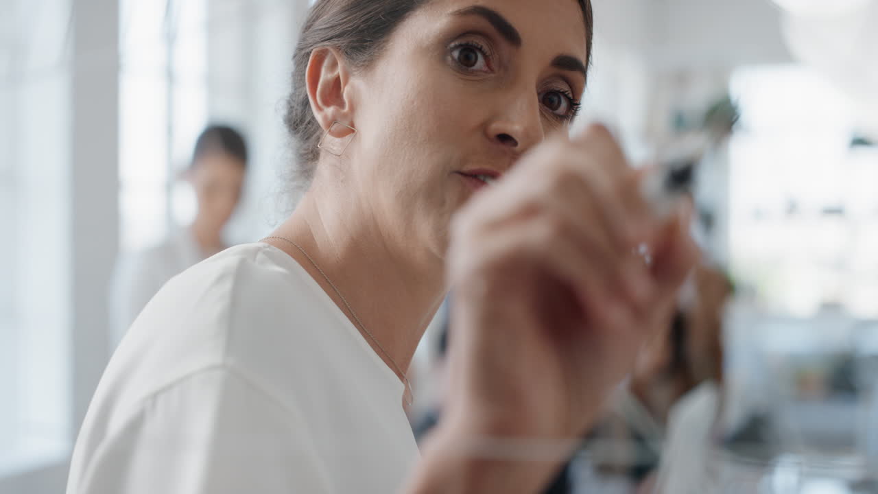 mujer líder de equipo de negocios escribiendo en una pizarra de vidrio capacitando a colegas compartiendo ideas para resolver problemas en una presentación de seminario corporativo