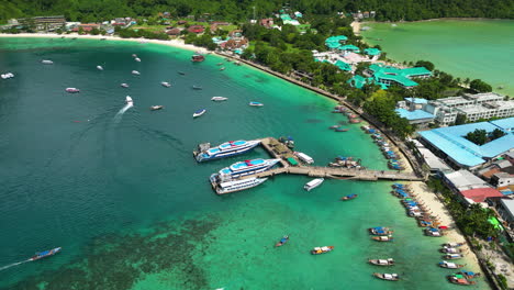 koh phi phi island harbor full of boats, ferries and hotel buildings, aerial shot orbital