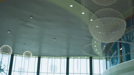 view of elegant chandeliers in a modern building interior, featuring both large and small chandeliers hanging from the ceiling. captured with a handheld camera