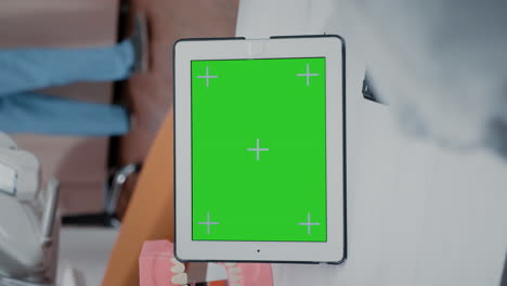 video vertical: primer plano del dentista usando la pantalla verde en la tableta