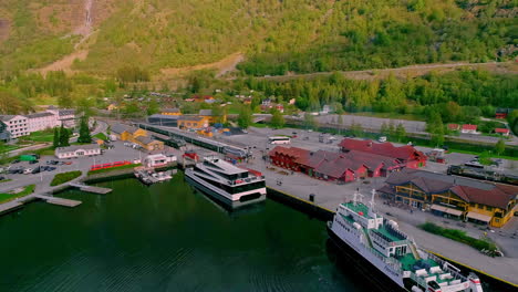 aerial backwards shot of ferry and industrial boat at port of flam in norway