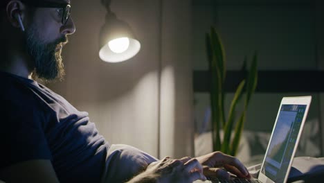 Side-view-of-man-working-in-bed-at-night