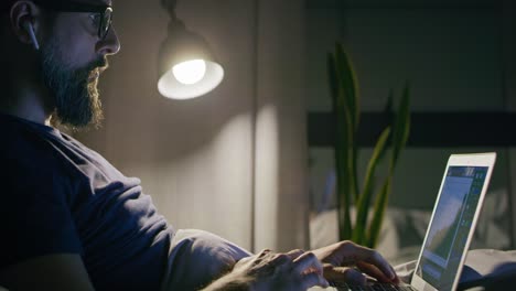 Side view of man working in bed at night