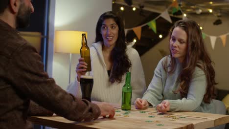 friends at home or in bar celebrating at st patrick's day party drinking alcohol and playing with novelty gold coins