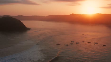 Sunrise-at-the-surf-spots-of-Gerupuk-in-Lombok,-with-a-view-on-the-bay-with-the-fishing-boats-and-surfers