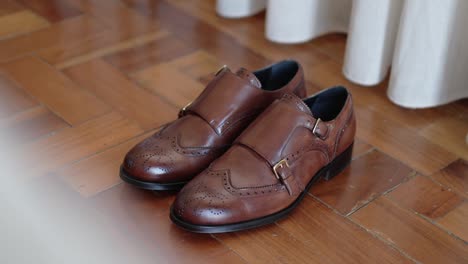 elegant brown leather monk strap shoes placed on polished wooden floor