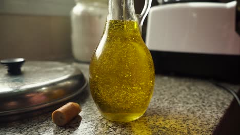 Close-Up-Of-Pouring-Olive-Oil-Into-Glass-Bottle-On-Kitchen-Counter