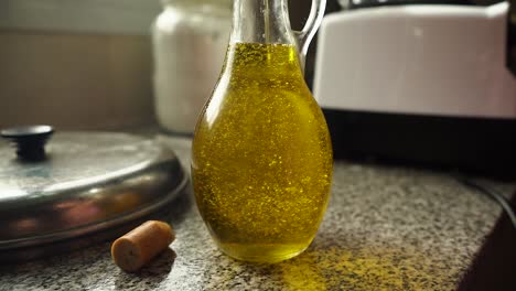 close up of pouring olive oil into glass bottle on kitchen counter