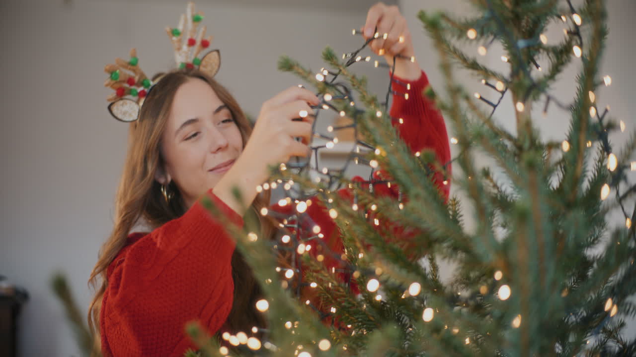 mujer ajustando las luces de led en el árbol de navidad