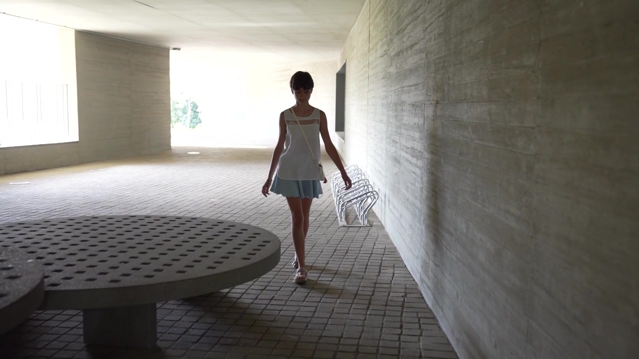 Una giovane donna elegante cammina in uno splendido e sorprendente spazio architettonico moderno.