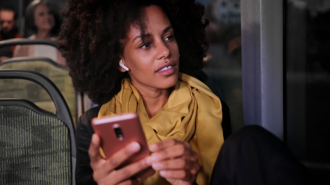 Close-up african-american woman with earphones and smartphone sitting on bus
