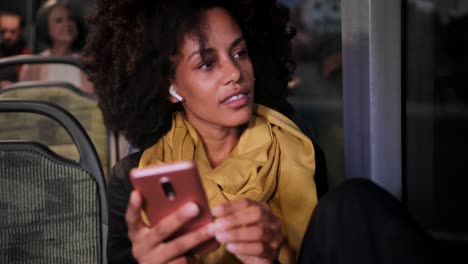 mujer afroamericana de primer plano con auriculares y teléfono inteligente sentada en el autobús
