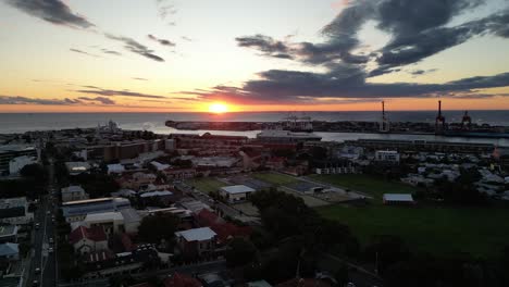 Vista-De-Drones-De-Una-Pequeña-Ciudad-En-Australia-Al-Atardecer-Con-El-Mar-Al-Fondo