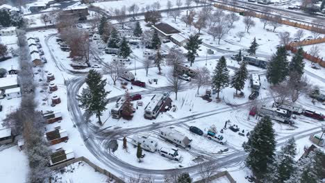 vista aérea ascendente de un parque de vehículos recreativos cubierto de nieve