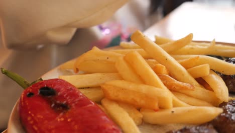 niño comiendo papas fritas y pimienta roja