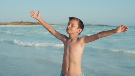 carefree boy enjoying summer at seashore. happy teenager standing at seaside.
