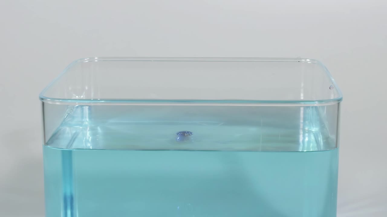 caída secuencial de bolas azules en un tanque de agua