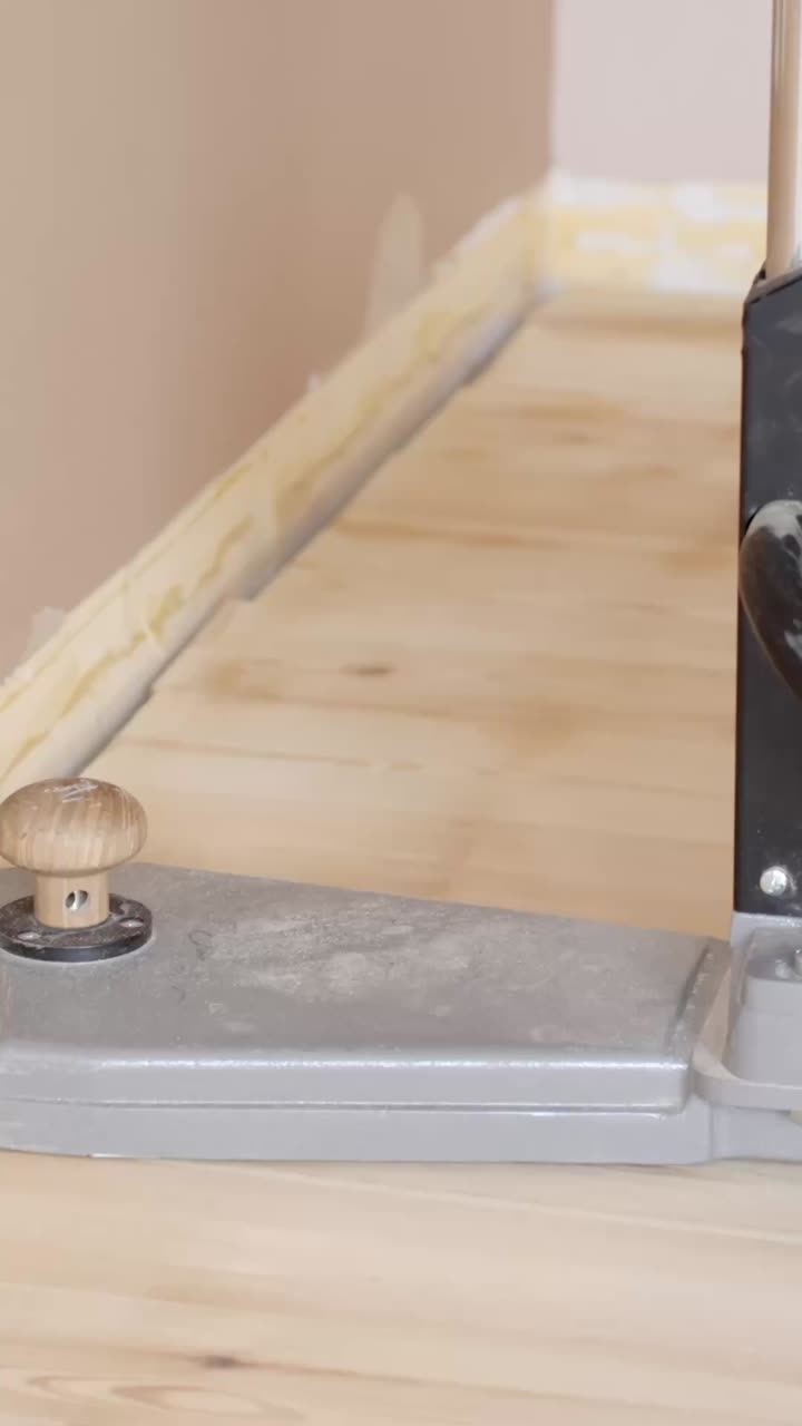 Close-up of sanding the edges of a wooden floor with a tool, focused on precision
