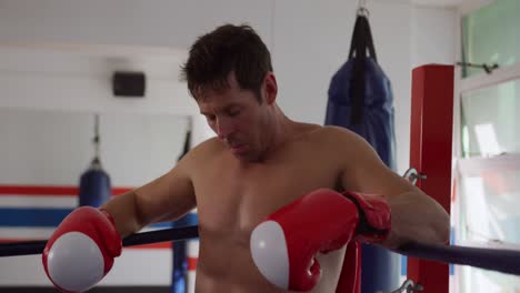 hombre caucásico descansando en el ring de boxeo