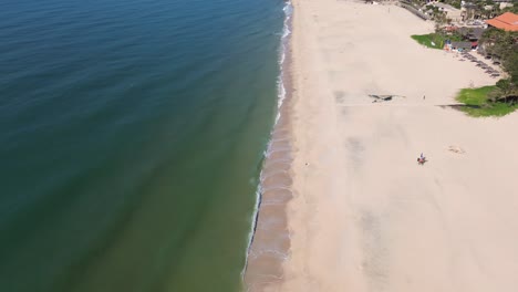 drone zooming out showing the expansive shoreline and calm ocean of mui ne, vietnam.