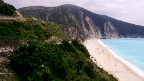 Vista-Costera-De-La-Playa-De-Myrtos-En-Cefalonia,-Grecia-Con-Aguas-Turquesas-Y-Fondo-Montañoso,-Vista-Aérea